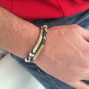 May include: A double-wrap bracelet with a black and yellow snake skin pattern and silver accents.