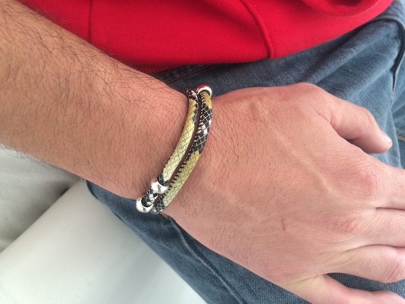 May include: A double-wrap bracelet with a black and yellow snake skin pattern and silver accents.