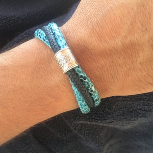 May include: A blue and black braided leather bracelet with a silver clasp.