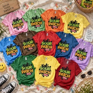 May include: A collection of eleven short-sleeved t-shirts in various colors including pink, green, orange, yellow, blue, brown, red, and purple. Each shirt features a central graphic with the text SOUR PATCH Kids in bold lettering.