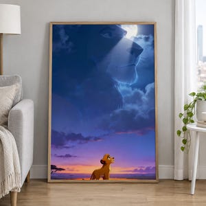Op de afbeelding: Een rechthoekige wandkunstprint in een lichthouten lijst met een scène uit The Lion King. Een kleine leeuwenwelp staat bij zonsondergang op de savanne en kijkt omhoog naar een grote, spookachtige, blauwe afbeelding van een volwassen leeuw.