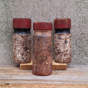May include: Three wooden bottle stoppers with red and black painted tops. The stoppers are weathered and have a rustic look.