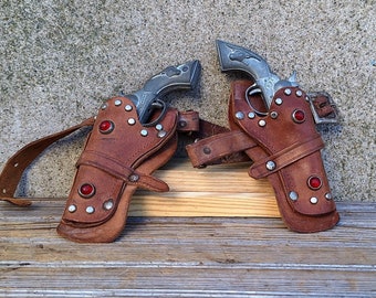 Pair of Vintage Working Toy Cast Hubley Tex Cap Guns with Period Leather and Jeweled Double Holster and Buckle in Original Condition