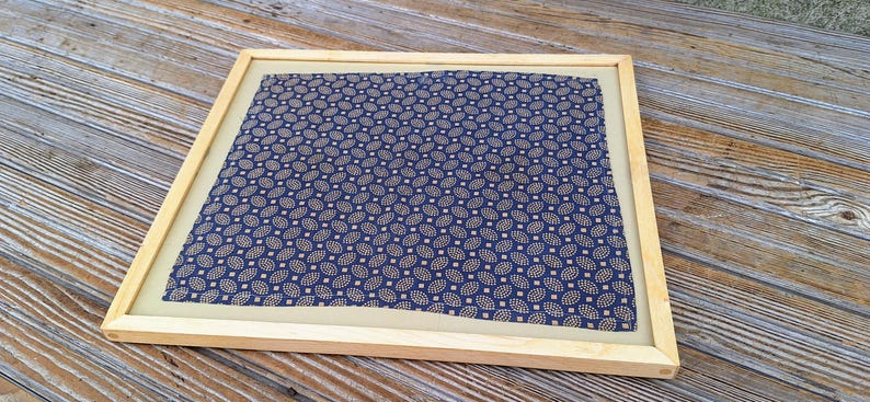 May include: A framed piece of fabric with a blue and gold pattern. The fabric has a repeating pattern of small, stylized leaves.