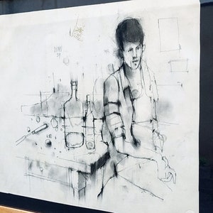 以下が含まれることがあります： テーブルにボトルとグラスを置いて座っている人の白黒の絵。絵は木製の額縁に入っています。