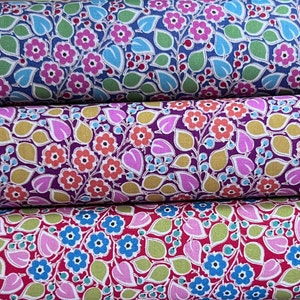 Op de afbeelding: Drie stofstalen met een bloemenpatroon. De bovenste staal is blauw met roze en witte bloemen, de middelste staal is paars met oranje en witte bloemen en de onderste staal is rood met blauwe en witte bloemen.
