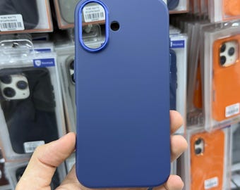 Puede incluir: Una funda de smartphone de color azul oscuro sólido con un acabado mate suave. La funda presenta un marco circular metálico azul prominente y elevado alrededor del recorte de la lente de la cámara y una pequeña abertura circular.