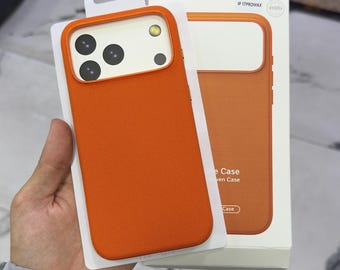 Puede incluir: Una funda de teléfono móvil de color naranja brillante con textura para IP 17PROMAX, que incluye un recorte para la cámara. La funda se presenta en su embalaje original de color blanco, con un gráfico naranja y el texto IP 17PROMAX.