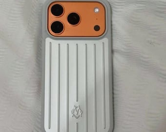 Puede incluir: Una funda de teléfono rectangular con un panel trasero de color plata metálico con estrías verticales y un pequeño logotipo en relieve en la parte inferior. La sección superior contiene una carcasa de cámara cobriza con tres aberturas.