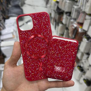 May include: A red smartphone case and a matching red magnetic card wallet, both covered in small, sparkling red crystals. The case features a circular magnetic ring on the back and a cutout for the camera lens, while the wallet has a rectangular shape.