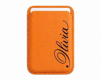 Puede incluir: Un tarjetero magnético rectangular de color naranja con esquinas redondeadas y costuras visibles en los bordes. El nombre Olivia está impreso en una fuente cursiva negra verticalmente en el lado derecho de la superficie.