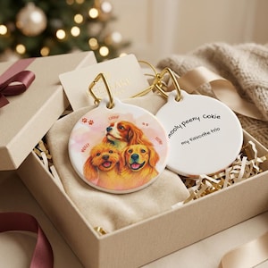May include: Two round white ceramic ornaments with gold metal loops. One ornament features a colorful illustration of three dogs with the names Mooly, Peeny, and Cokie. The other ornament has the text mooly peeny cokie and my favorite trio.