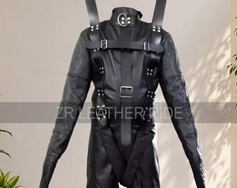May include: A black leather restraint suit featuring long sleeves, a high collar with a metal ring, and multiple adjustable buckled straps across the chest and torso. The garment includes shoulder straps with large metal rings and the text ZR LEATHER HIDE.