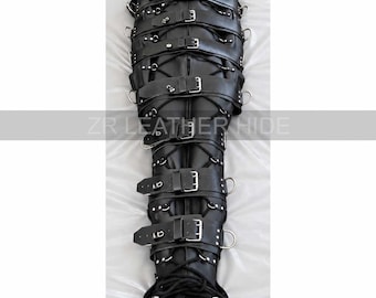 May include: A black leather full-body restraint bag featuring a head hood, multiple horizontal buckled straps, and integrated metal D-rings along the sides. The text ZR LEATHER HIDE is printed across the centre of the black leather garment.