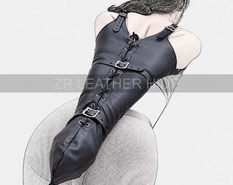 May include: A black leather straight jacket featuring a front lace-up closure with metal eyelets, adjustable buckled straps across the chest and midsection, and shoulder straps. The garment includes a metal D-ring at the bottom and text ZR LEATHER HUE.