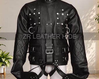May include: A black leather straightjacket featuring a high collar with a buckle, silver-toned metal D-rings, and multiple straps across the chest and torso. The sleeves have a quilted diamond pattern, and the text ZR LEATHER HIDE is visible.