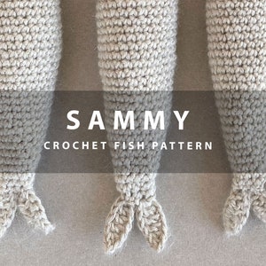 K&ouml;nnte beinhalten: Drei geh&auml;kelte Fischspielzeuge in Beige, mit dem Text "SAMMY CROCHET FISH PATTERN" in Schwarz.