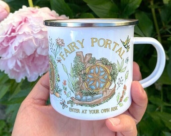 Könnte beinhalten: Weißer Emaillebecher mit silbernem Rand, mit den Worten "Fairy Portal" in goldfarbenen Buchstaben. Der Becher hat ein skurriles Design mit einer Feentür, Blumen und einem Kolibri. Der Text "Enter at your own risk" steht unten.