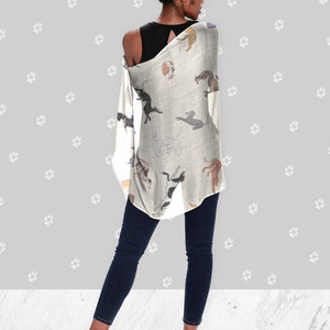 A woman wearing a black tank top, jeans, black heels and a beige modal scarf with illustrated greyhound dog pattern on it draped over her shoulders.