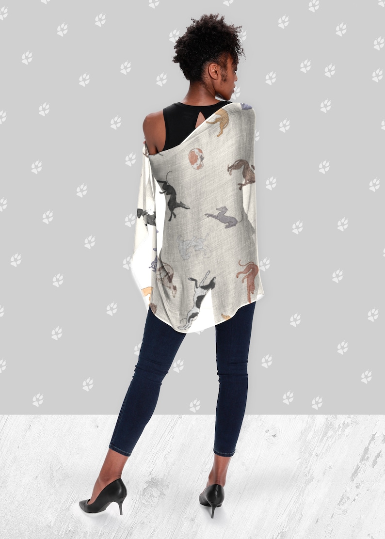 A woman wearing a black tank top, jeans, black heels and a beige modal scarf with illustrated greyhound dog pattern on it draped over her shoulders.