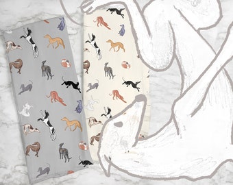Könnte beinhalten: Zwei gefaltete Küchentücher mit einem sich wiederholenden Muster von Windhunden in verschiedenen Posen und Farben. Ein Handtuch ist hellgrau, das andere cremefarben. Die Hunde sind in Braun-, Schwarz-, Grau- und Weißtönen gehalten.