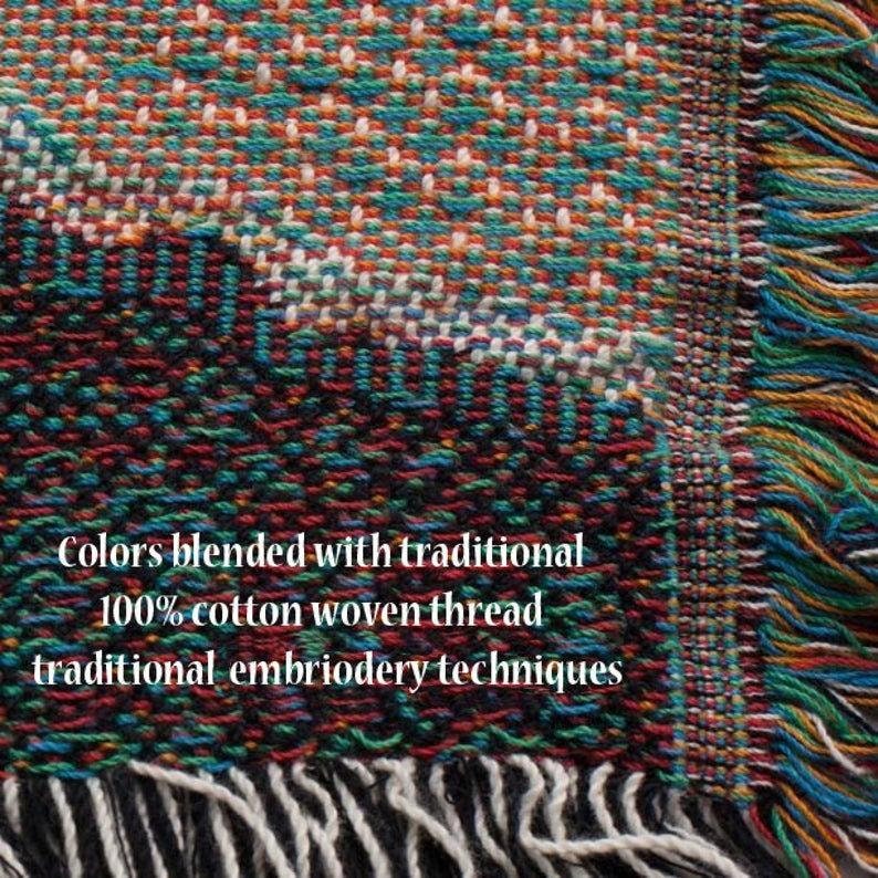 K&ouml;nnte beinhalten: Nahaufnahme eines gewebten Textils mit einer Mischung aus Farben wie T&uuml;rkis, Orange, Rot und Wei&szlig;. Der Text lautet: "Farben gemischt mit traditionellem 100% Baumwoll-Webfaden traditionellen Sticktechniken."
