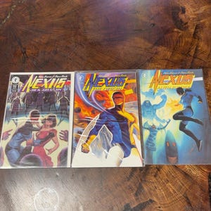 May include: Three Nexus comic books by Mike Baron and Steve Rude. The left cover is titled The Wages of Sin, the center is The Origin, and the right is Alien Justice. Each comic features colorful, detailed illustrations of characters in action.
