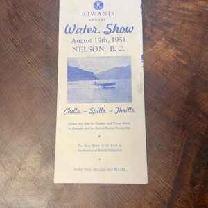 May include: A vintage off-white paper program for the Kiwanis Annual Water Show held on August 19th, 1951, in Nelson, B.C. The document features blue text, a central illustration of a motorboat on a lake, and the slogan Chills - Spills - Thrills.