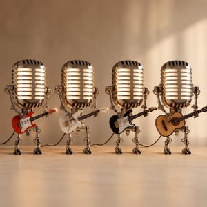 Könnte beinhalten: Vier metallische roboterförmige Lampen mit Vintage-Mikrofonköpfen. Jeder Roboter hat bewegliche Gliedmaßen und hält eine Miniaturgitarre: eine rote E-Gitarre, eine weiße, eine schwarze und eine akustische Gitarre aus hellem Holz.