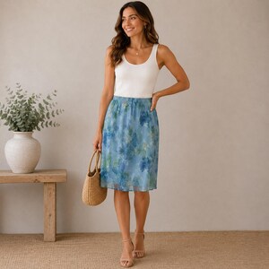 May include: A white ribbed tank top paired with a knee-length blue skirt featuring a watercolor-style floral print in shades of blue and green. The skirt has a gathered elastic waistband and a lightweight, semi-sheer layered appearance.