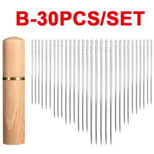 May include: A set of 30 silver-colored metal sewing needles arranged in a fan shape next to a cylindrical light brown wooden needle storage case with a gold-colored metal band. The text B-30PCS/SET is printed in red at the top.