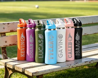 May include: Seven cylindrical water bottles in orange, purple, olive green, light blue, white, light pink, and black. Each bottle features a sports ball graphic with flames and a name engraved vertically: KEVIN, LOGAN, LUCAS, TYLER, GAVIN, CALEB, and ISAAC.