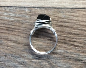 May include: A silver wire wrapped ring with a black gemstone.
