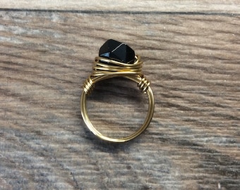 May include: A gold wire wrapped ring with a black faceted gemstone.
