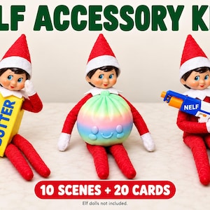 May include: An elf accessory kit featuring three elf dolls. One elf wears a yellow butter box costume, one holds a round rainbow-colored dumpling toy, and one holds a blue and white toy blaster labeled NELF. Text reads ELF ACCESSORY KIT and 10 SCENES + 20 CARDS.