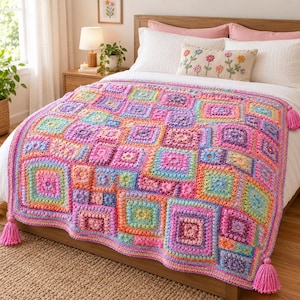 May include: A handmade crochet blanket featuring a vibrant patchwork of multicolored granny squares in shades of pink, purple, orange, yellow, and blue. The rectangular throw is finished with a matching pink border and large tassels at each corner.