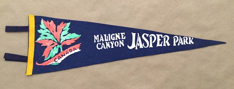 May include: A blue felt pennant with a yellow border and a red, green, and white maple leaf design. The pennant reads "Malign Canyon Jasper Park" and "Canada".