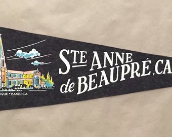 Könnte beinhalten: Ein schwarzer Filz-Wimpel mit roter Franse. Der Wimpel zeigt eine weiße Illustration einer Kirche mit dem Text "Ste-Anne de Beaupre, Canada".