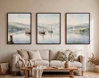 May include: A set of three vertical wall art prints in black frames, each featuring a watercolour landscape of sailboats on a calm lake with misty green hills in the background. The artwork displays soft blue, green, and neutral tones, depicting a serene maritime scene with reflections on the water surface and a wooden post in the foreground of the left print.