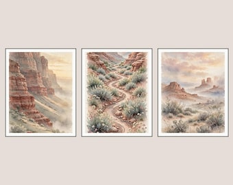 May include: A set of three framed watercolour prints depicting desert landscapes. The left shows canyon walls, the centre features a winding path through sagebrush, and the right displays distant rock formations under a soft, hazy sky.
