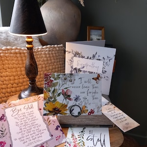 May include: A set of four sympathy cards with floral designs and inspirational quotes. The cards feature watercolour flowers in shades of pink, purple, yellow, and green. The quotes include "Be Still", "I will never leave thee, nor forsake thee", "Be Still and Know that I am God", and "Sympathy".