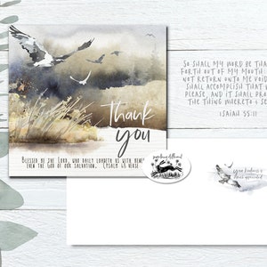 May include: A watercolor thank you card with a quote from Isaiah 55:11. The card features a watercolor background with birds flying over a field of grass. The text "Thank you" is written in black ink.