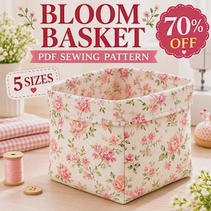 May include: A square fabric basket featuring a cream background with a pink and green floral pattern. The text on the image reads Bloom Basket, PDF Sewing Pattern, 5 Sizes, and 70% Off. The basket is shown with sewing supplies nearby.