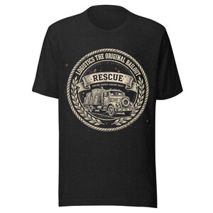 Könnte beinhalten: Ein schwarzes Kurzarm-T-Shirt mit einem kreisförmigen Motiv, das von einem Seil und Lorbeerblättern umrahmt ist. Das Design zeigt einen alten Lastwagen mit Kisten und den Text: LOGISTICS THE ORIGINAL BAILOUT, RESCUE, SAVING SUPPLY CHAINS DAILY.