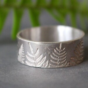Op de afbeelding: Een zilveren ring met een varendesigne. De ring is breed en heeft een gladde, gepolijste afwerking.