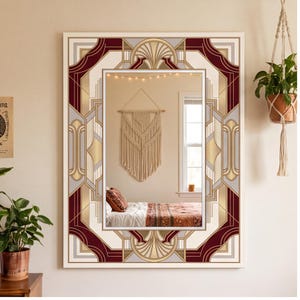 May include: A rectangular wall mirror featuring a decorative frame with a geometric pattern in shades of deep red, gold, and light gray. The frame design includes symmetrical fan-like motifs at the top and bottom edges, surrounding a clear glass.