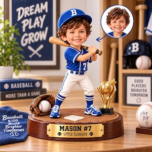 May include: A custom bobblehead figurine of a young baseball player wearing a blue cap with a B, a blue jersey with the number 7, and white trousers. The figure stands on a wooden base with a gold plaque reading MASON #7 LITTLE SLUGGER.