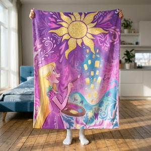 Könnte beinhalten: Eine violette Fleecedecke mit einer grafischen Illustration einer langhaarigen Figur, die einen Pinsel und eine Palette hält. Das Design zeigt eine große gelbe Sonne, schwebende Laternen, eine kleine grüne Eidechse und florale Muster.
