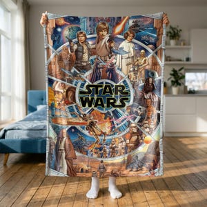 Könnte beinhalten: Eine rechteckige Wohndecke mit einem farbenfrohen Star Wars-Collage-Druck. Das Design zeigt Luke Skywalker, Prinzessin Leia, Han Solo, Chewbacca, Darth Vader sowie verschiedene Droiden und Raumschiffe um ein zentrales Star Wars-Logo.