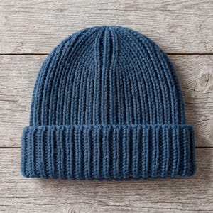 May include: A solid dark blue beanie crafted with a thick, vertical ribbed knit pattern. The hat features a wide, folded cuff at the base and a rounded crown, showcasing a consistent, textured yarn construction throughout the entire garment.